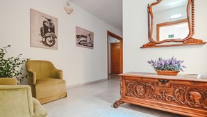 Ein Flur mit einem Holzschrank, zwei Sesseln und Wandbildern.