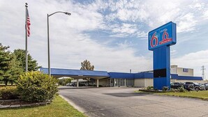 A 6.6 Extended Sky motel with a blue roof, an American flag, and a parking lot. - Concorde Inn Suites Pekin (Pekin)