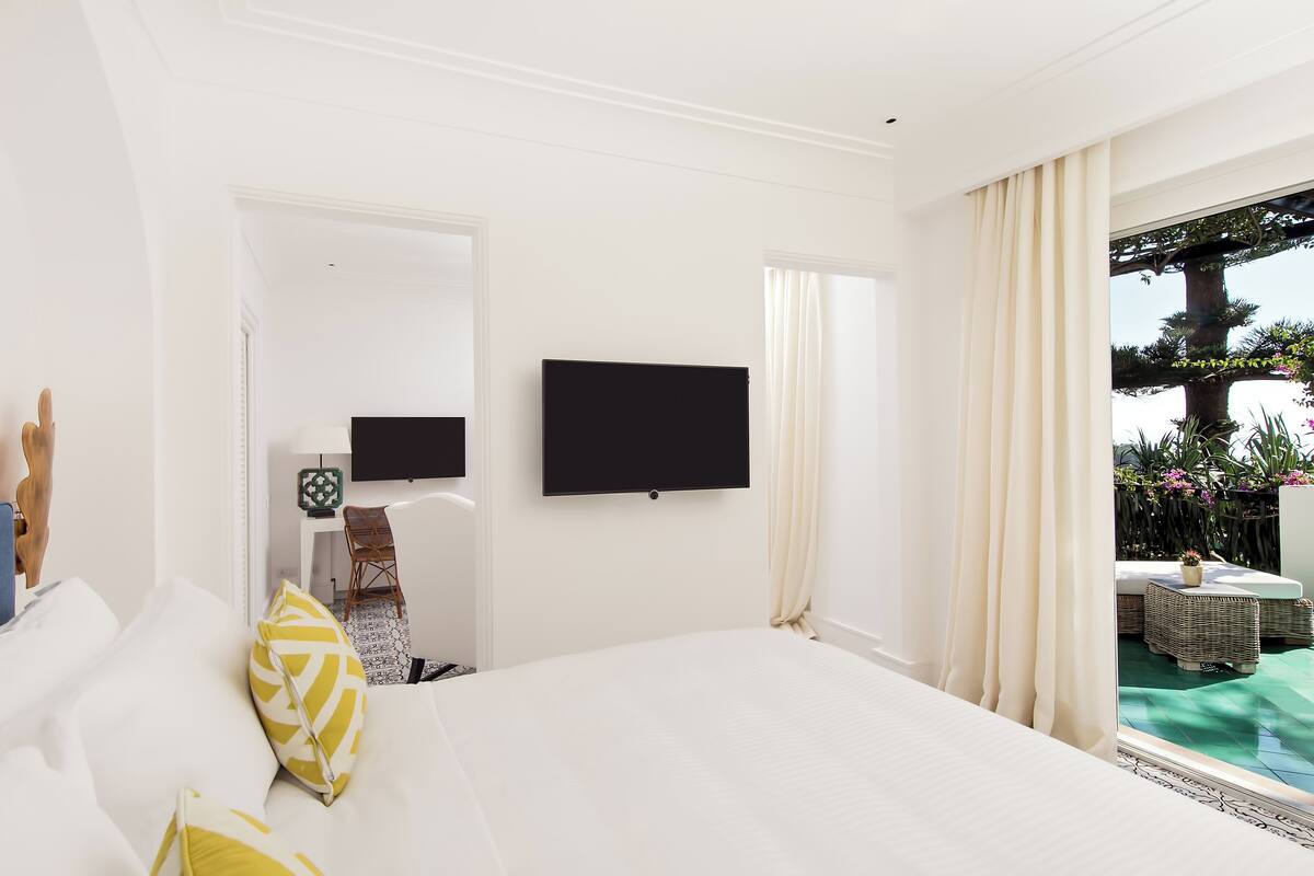 Habitación de hotel con una cama grande, televisión de pantalla plana, escritorio con silla y vista a una piscina y zona exterior.