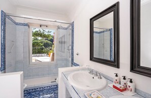 A bathroom with a large mirror, a bathtub, a shower, and a sink.
