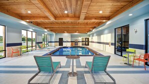 An indoor swimming pool area with a wooden ceiling, tiled floor, and colorful chairs. - Home2 Suites by Hilton Oklahoma City Airport (Oklahoma City)