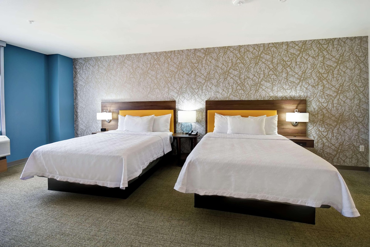 Ein Hotelzimmer mit zwei Betten, einer Wand mit Muster und einer blauen Akzentwand.