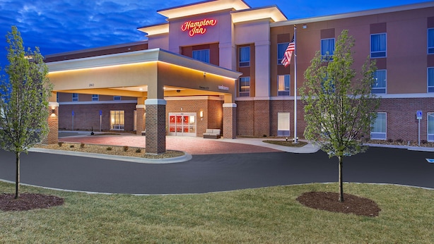 Modernilla designilla varustettu Hampton Inn -hotelli, jossa on valaistu sisäänkäynti, katettu ulkoalue ja tiiliverhous.