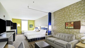 A hotel room with a bed, a sofa, a desk, and a TV. - Home2 Suites by Hilton Brownsville (Brownsville)