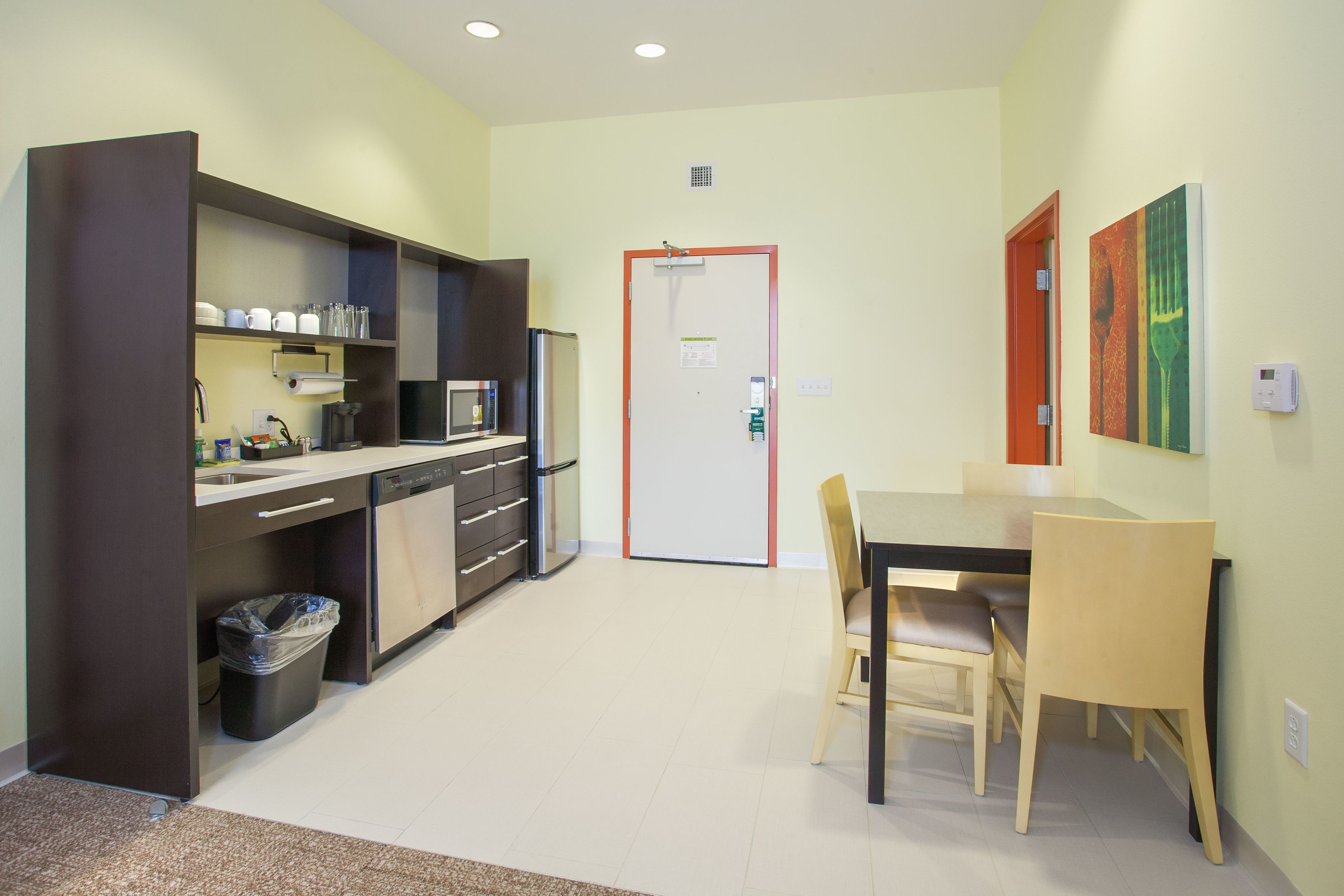 A compact kitchen with modern appliances, a dining area with a table and chairs, and a door leading to another room.