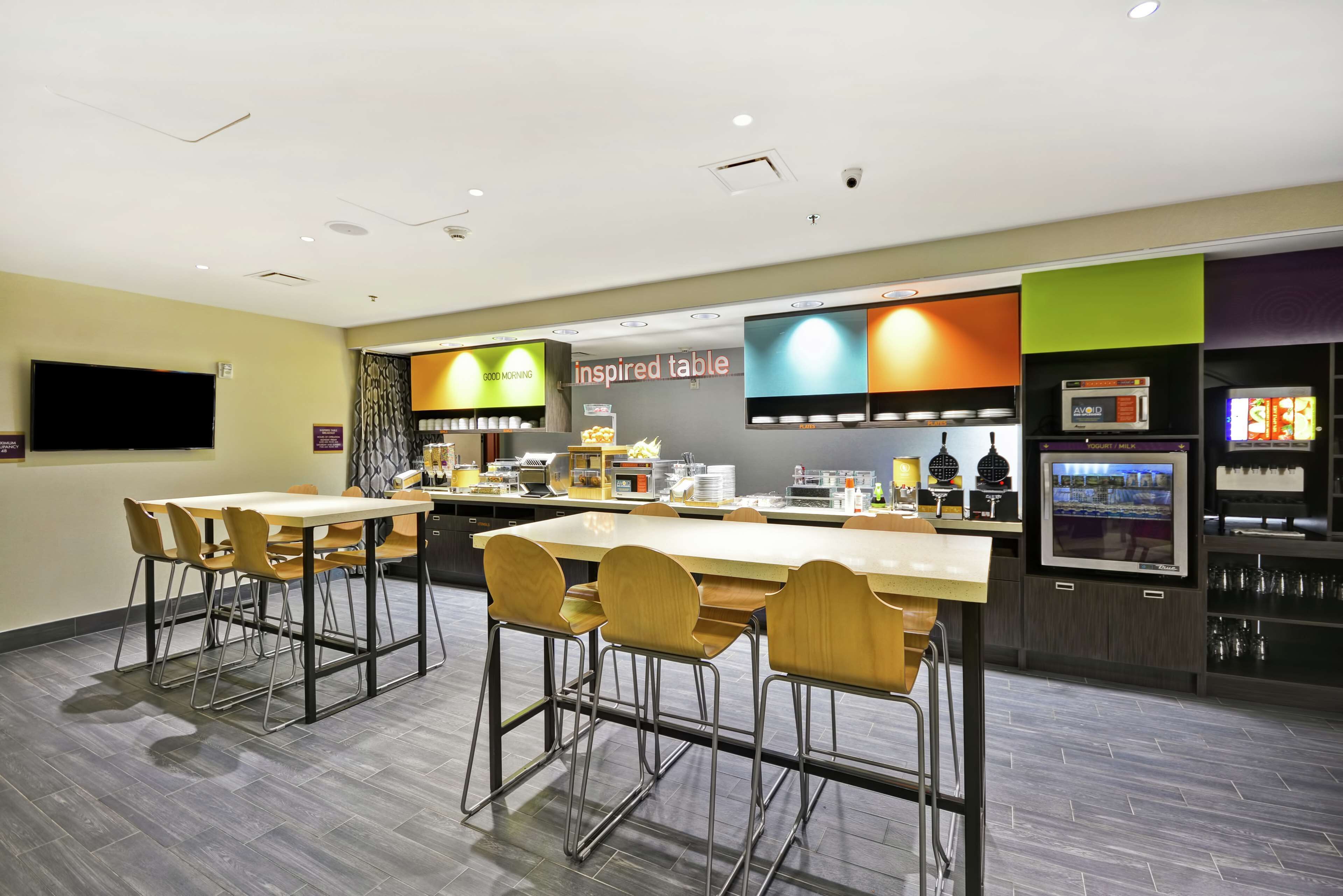 A modern restaurant with a long counter, multiple seating options, and a variety of food and drink displays.