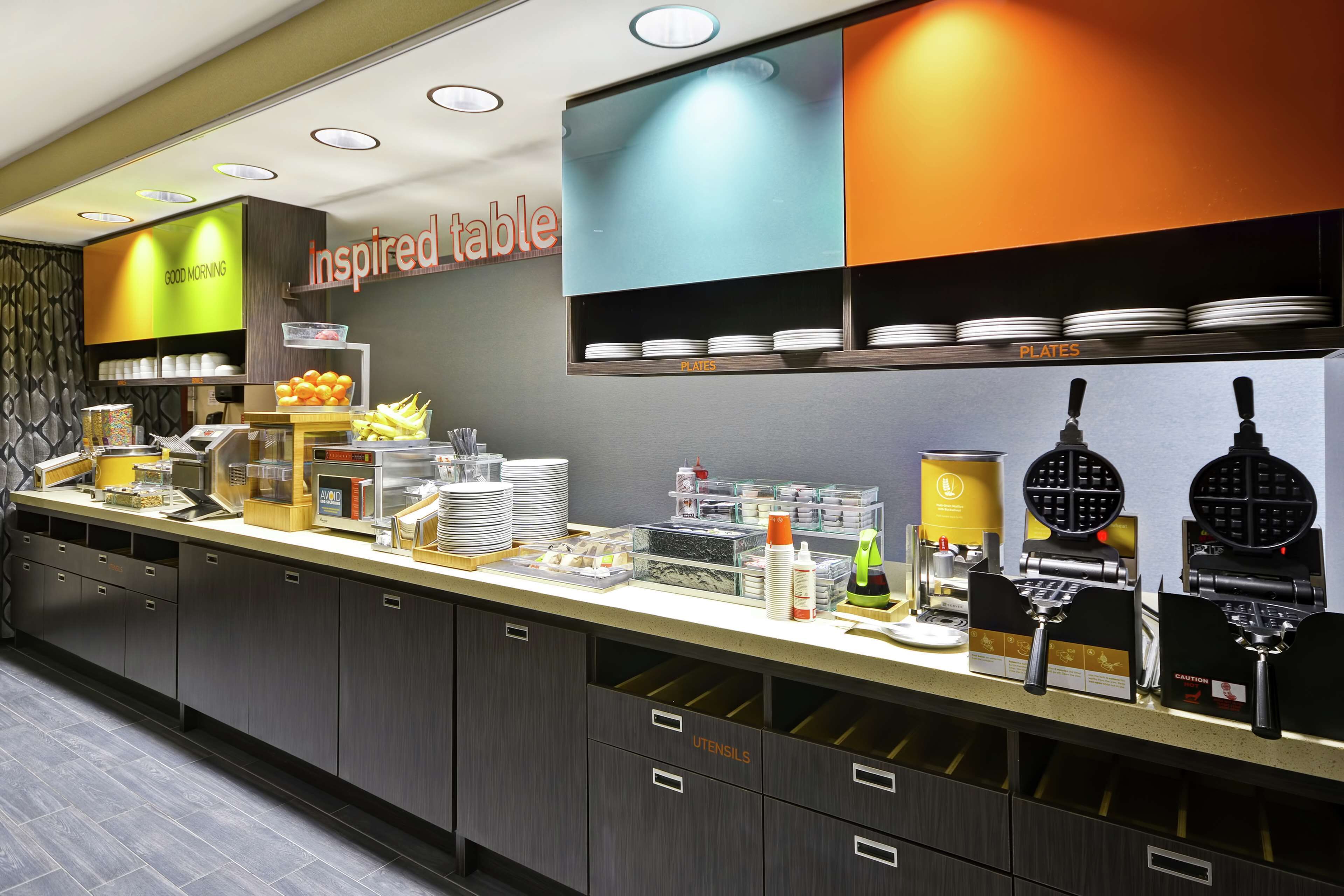 Cozinha moderna com bancada exibindo diversos utensílios e eletrodomésticos, incluindo máquinas de waffle e cafeteira.