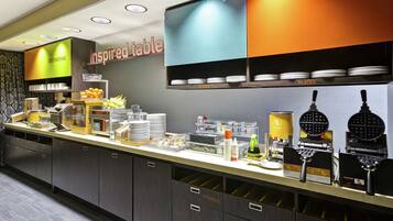 Cozinha moderna com bancada exibindo diversos utensílios e eletrodomésticos, incluindo máquinas de waffle e cafeteira.