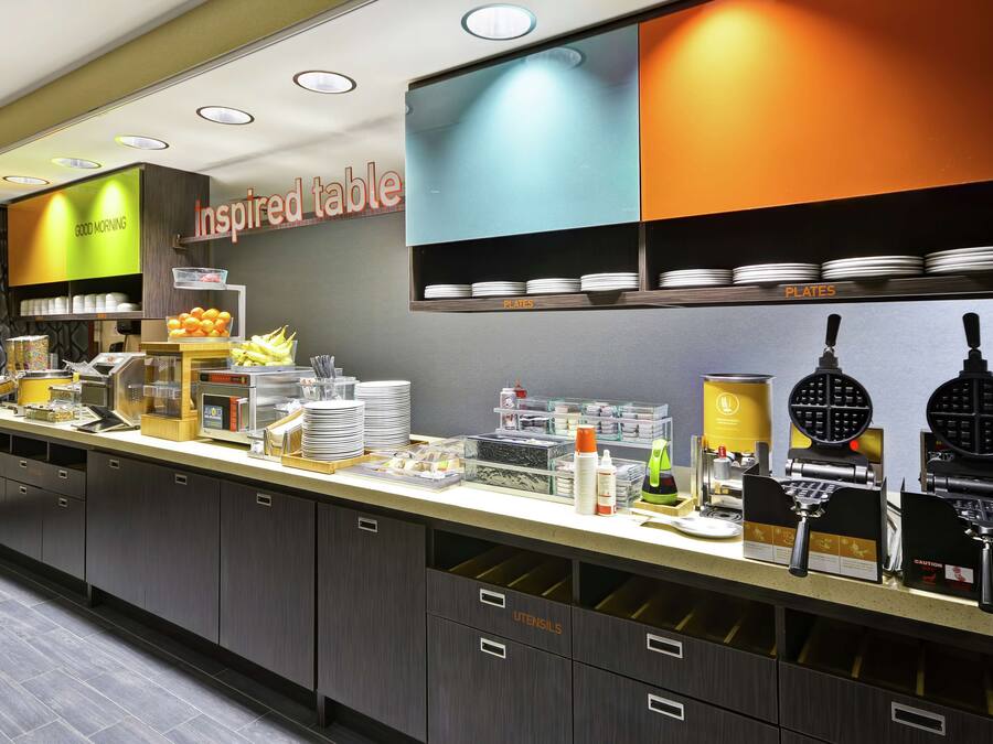 Cozinha moderna com bancada exibindo diversos utensílios e eletrodomésticos, incluindo máquinas de waffle e cafeteira.