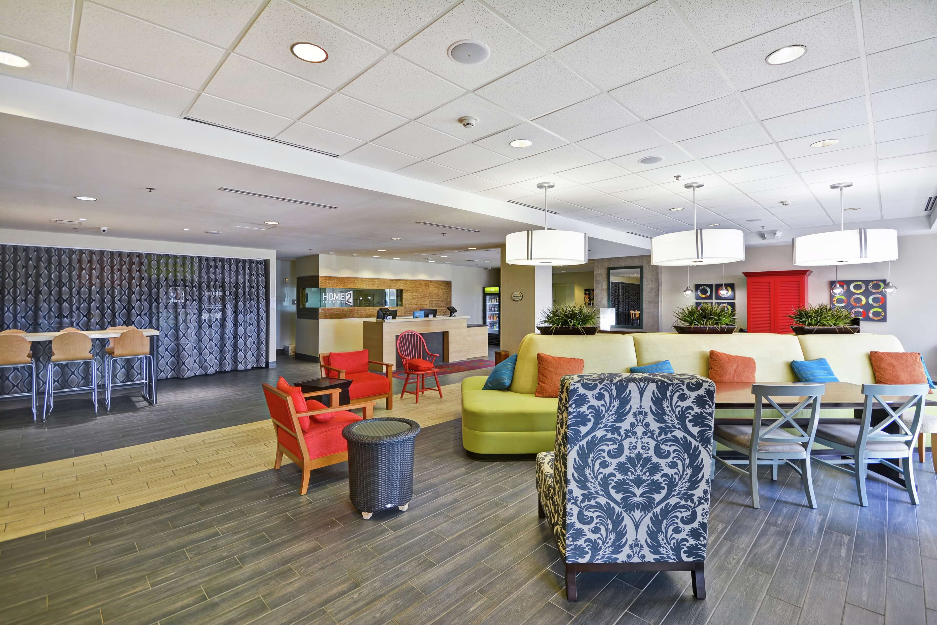 A modern hotel lobby with a reception desk, seating area, and a dining space.