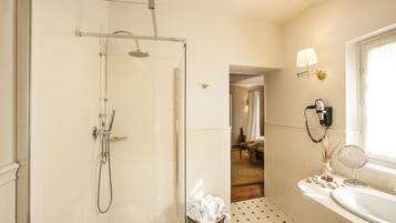 A modern bathroom with a glass-enclosed shower, a sink with a mirror, and a window with a curtain.