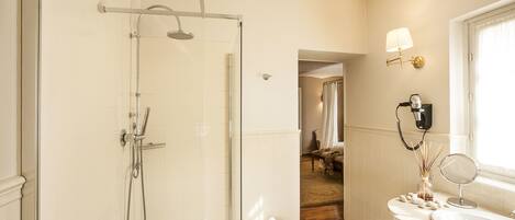 Un baño moderno con ducha de vidrio, lavamanos con espejo y ventana con cortina.
