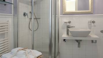 A bathroom with a glass-enclosed shower, a white sink, and a mirror above it.