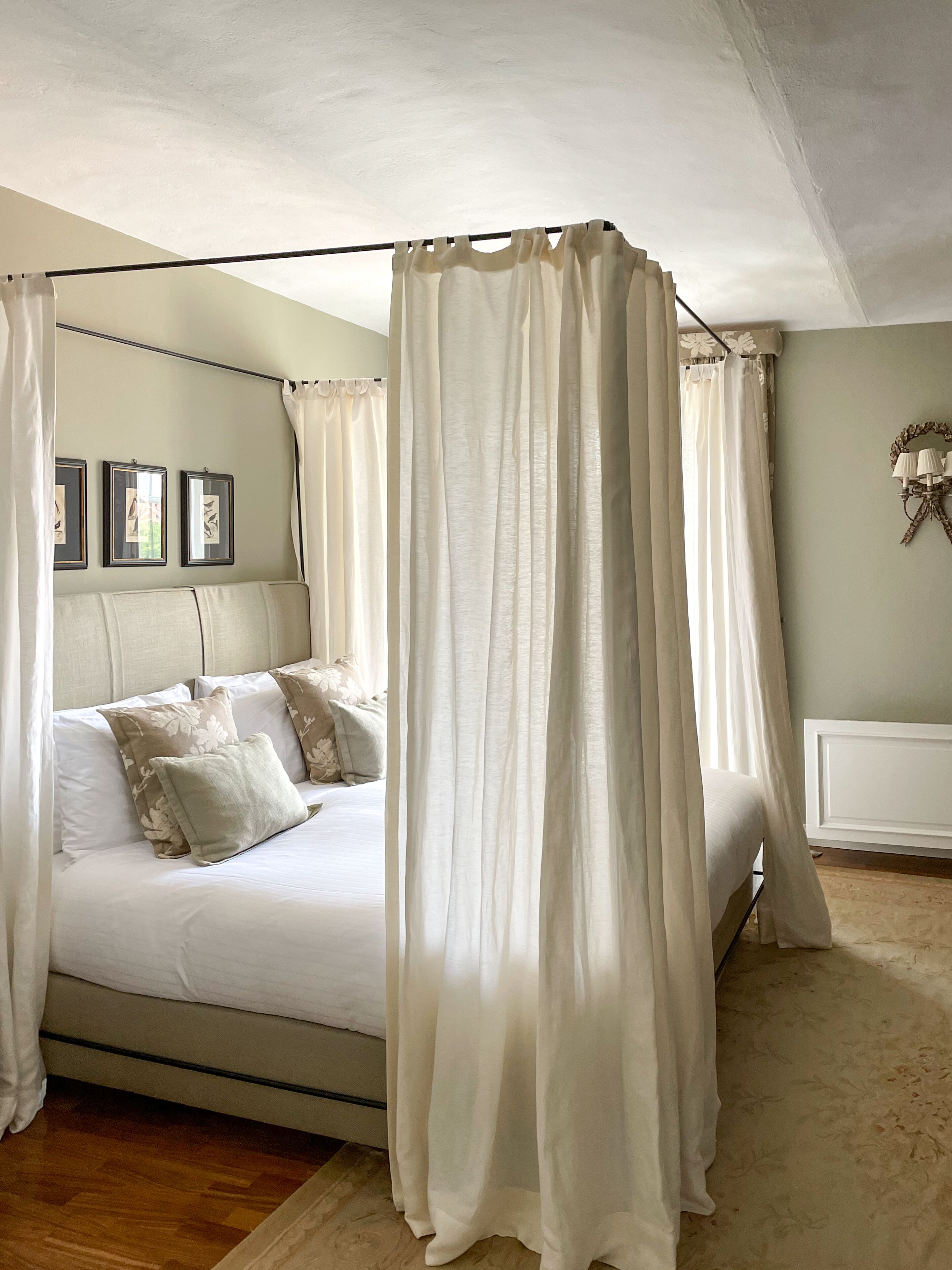 Une chambre à coucher avec un lit à baldaquin, un dais et une lampe fixée au mur.