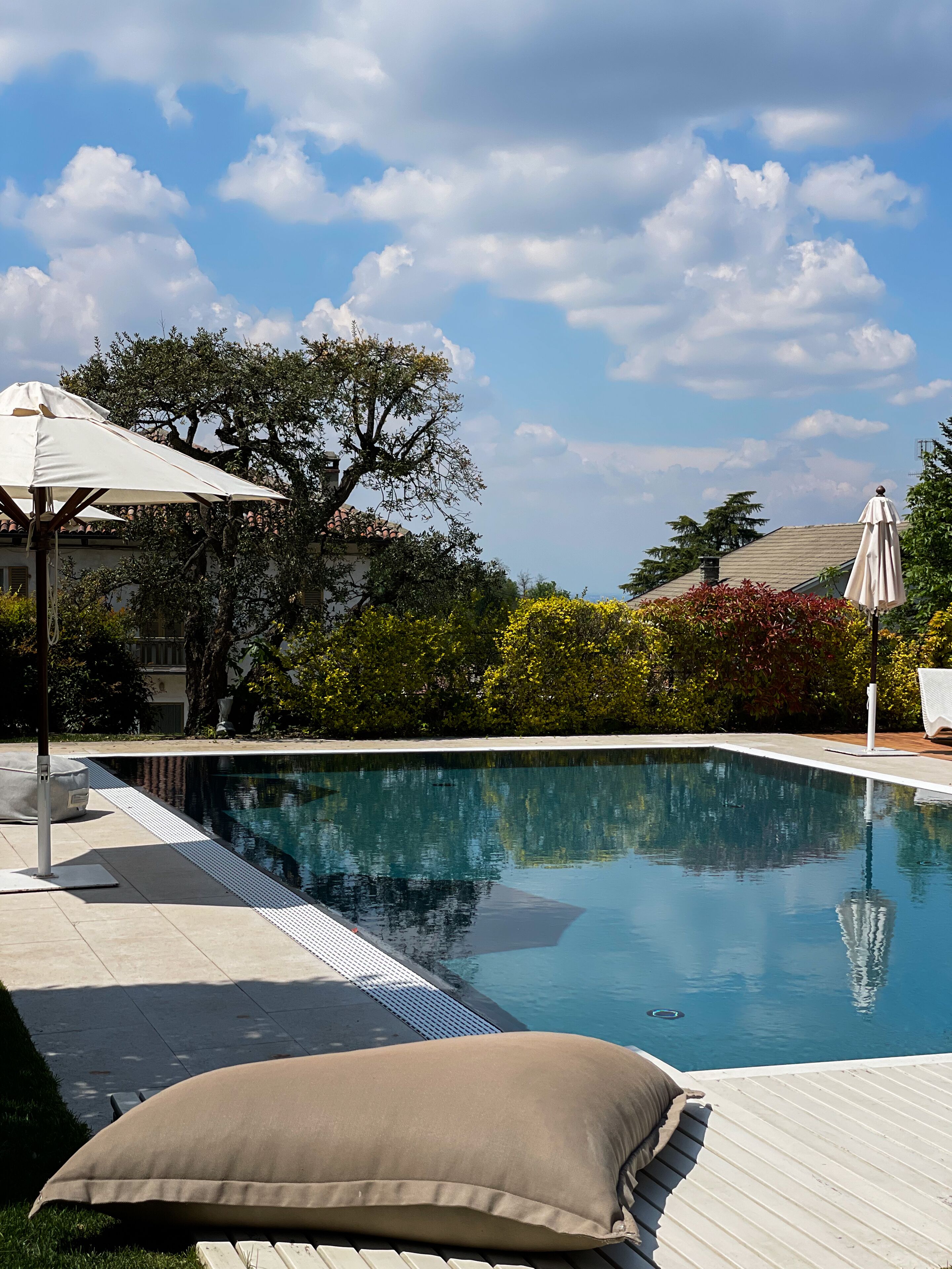 Piscina com superfície de água azul cristalina, rodeada por um espaço de deck com espreguiçadeiras e guarda-sóis.