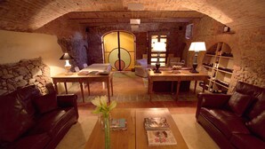 Une pièce chaleureuse avec un plafond en briques, des canapés en cuir, une table basse en bois avec des magazines et un vase rempli de fleurs.