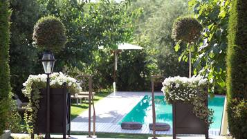 Area piscina con un pergolato, un lampione e un siepe ben curata.