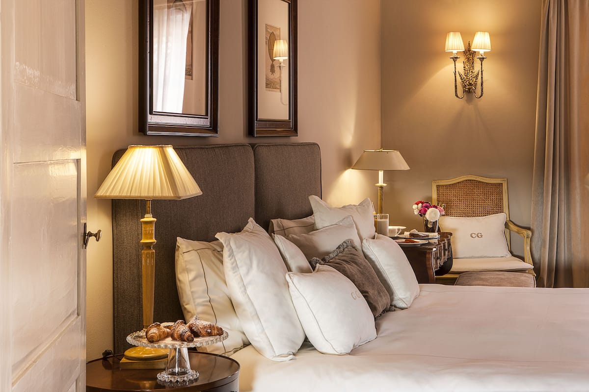 A hotel room with a large bed, two bedside tables, a lamp, a framed picture, and a wall-mounted light fixture.