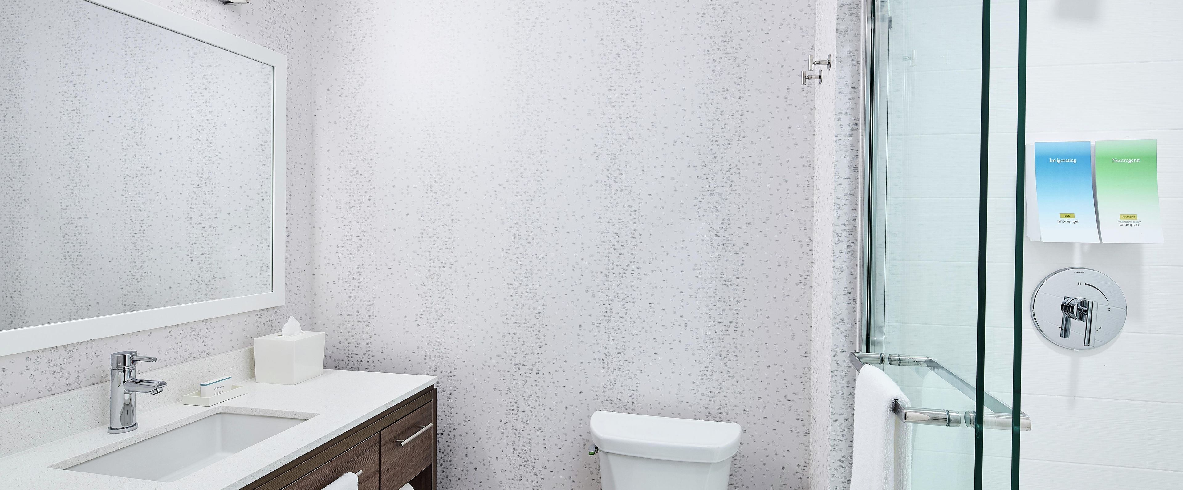 Ein Badezimmer mit Waschbecken, Spiegel, Toilette und Duschbereich.