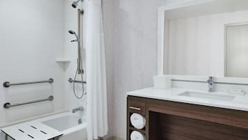 A bathroom with a shower, a sink, a mirror, and a towel rack.