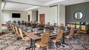 A conference room with long tables, chairs, and a large mirror on the wall.