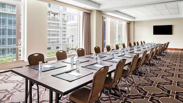 A conference room with a long table, chairs, and a TV screen.