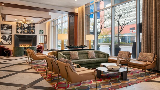 A modern lobby with a fireplace, comfortable seating, and large windows offering a view of the outside. - Home2 Suites by Hilton Chicago McCormick Place (Chicago)