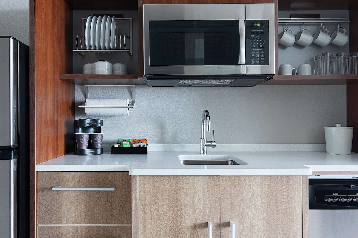 A modern kitchen with a stainless steel refrigerator, a microwave, a sink, and a dishwasher.