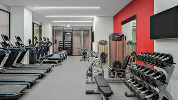 Uma academia com esteiras, halteres e máquinas de musculação.