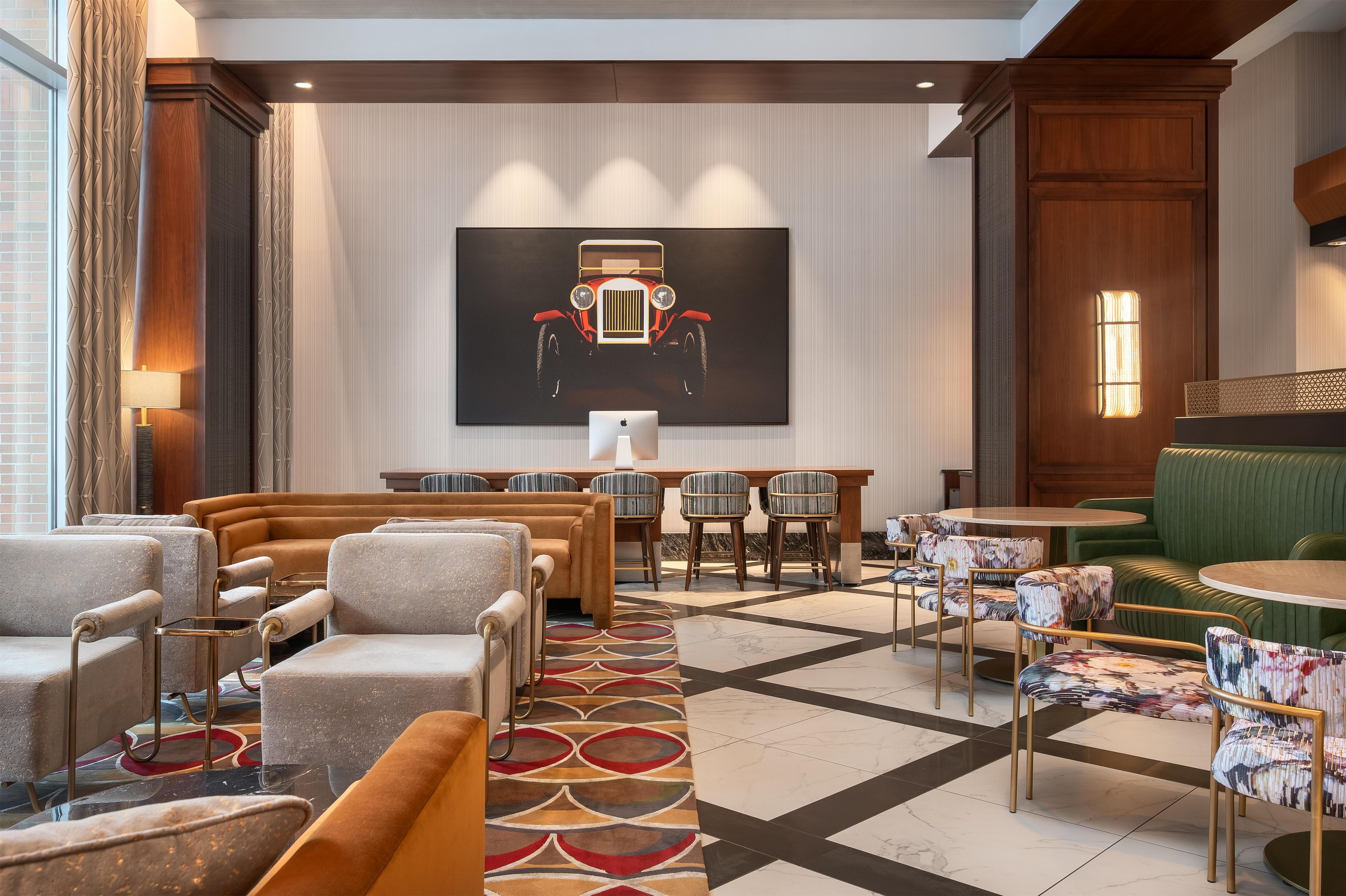 Um hall de hotel com uma pintura grande, diversas áreas de estar e um chão estampado.