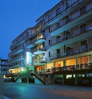 Un hotel de varios pisos con balcones, una escalera y un letrero que indica el nombre.