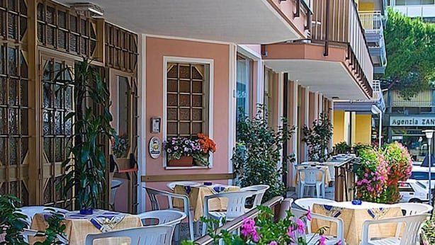 Un café en plein air avec des tables et des chaises, entouré de plantes et de fleurs en pot.