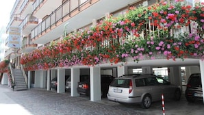 Un hôtel doté d’un parking à plusieurs niveaux et d’un balcon agrémenté de plantes en fleurs.