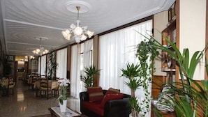 Un hall d’entrée spacieux, avec un canapé rouge, une table basse et des plantes en pot.