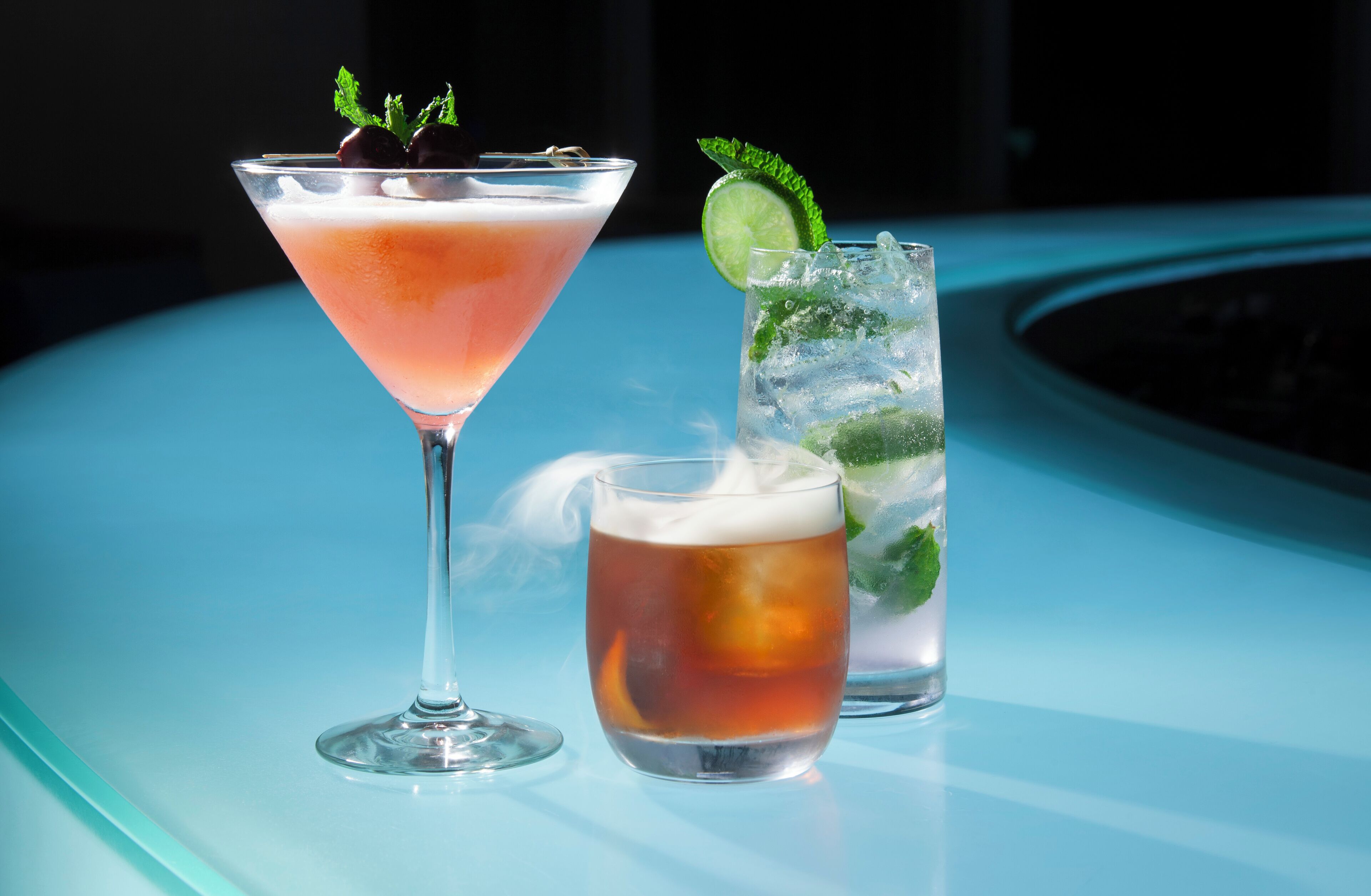 Three drinks on a table with a blue surface.