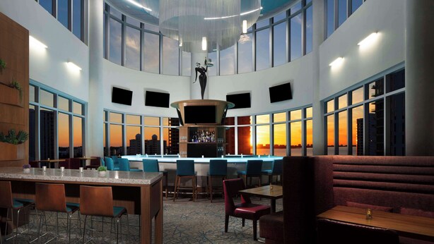 Un vaste espace intérieur doté d’un haut plafond, de grandes fenêtres et d’un bar central.