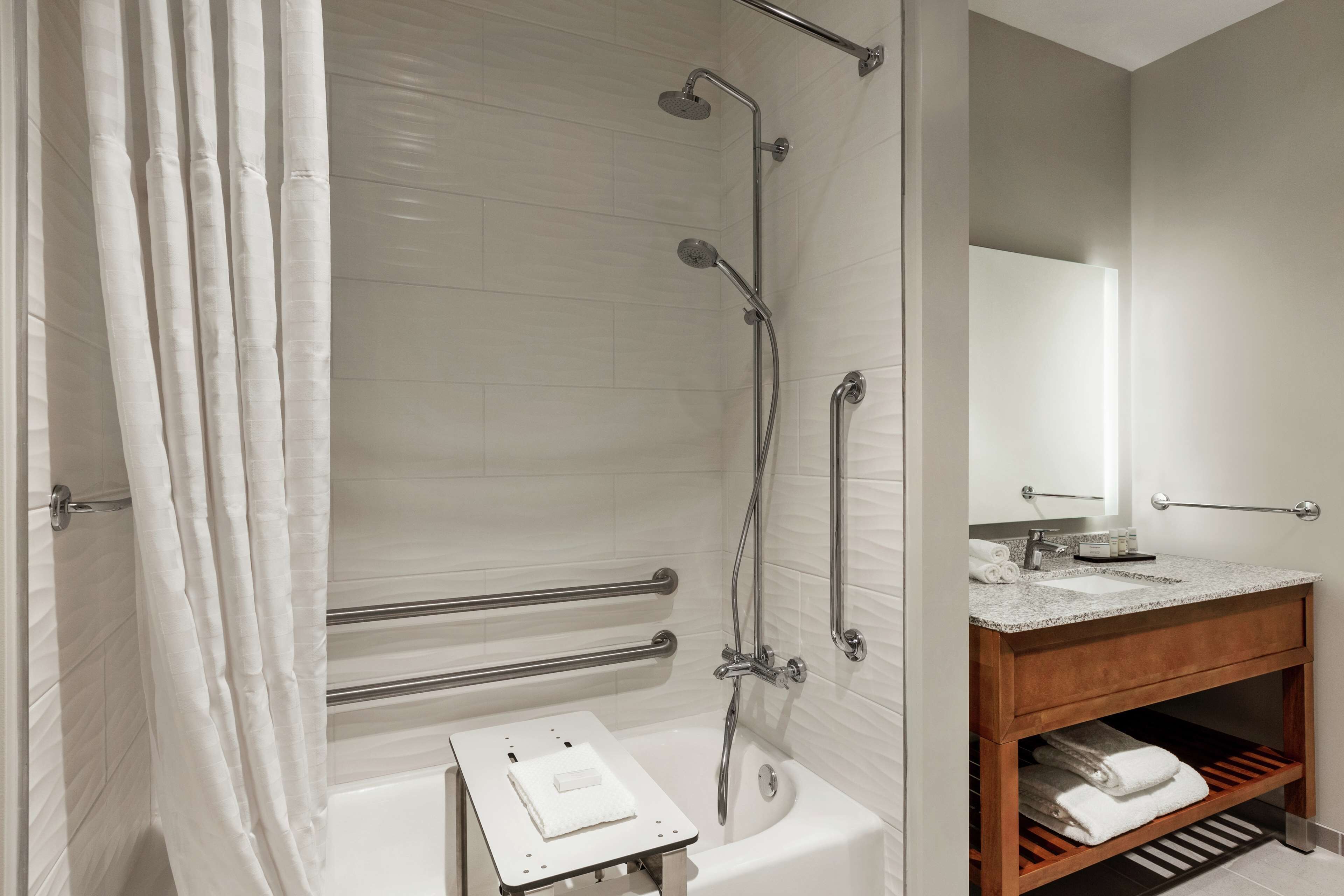 A modern bathroom with a bathtub, shower, and vanity.