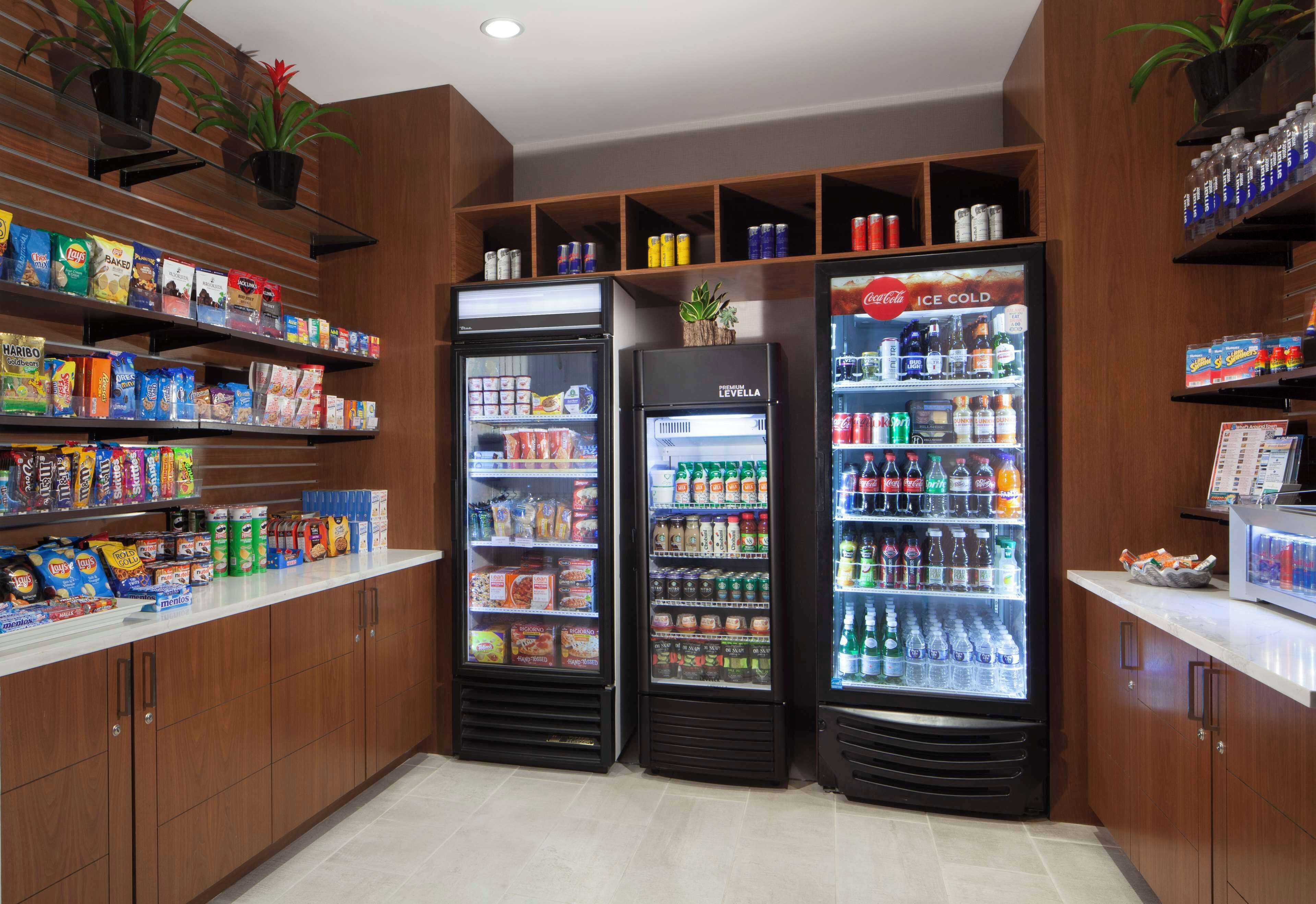 Un espace de libre-service où l’on peut se servir des boissons, avec des distributeurs de boissons réfrigérés et des étagères remplies de collations et de boissons.