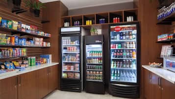 Una estación de autoservicio para bebidas, con dispensadores refrigerados y estantes llenos de refrigerios y bebidas.