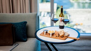 Une table avec une bouteille de vin, deux verres de vin, un bol de beurre et des tranches de pain sur une planche en bois.