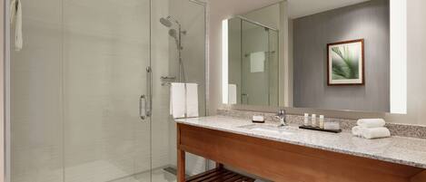 A modern bathroom with a glass-enclosed shower, a wooden vanity with a marble countertop, and a large mirror above the sink.