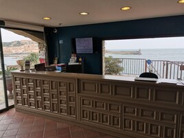 Un comptoir d’accueil offrant une vue sur la mer et sur les bâtiments qui se dressent à l’arrière-plan.
