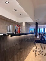 Un área de bar moderna con mostrador, taburetes y vista al comedor.