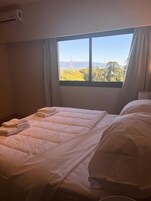 Una habitación de hotel con una cama, una ventana y un equipo de aire acondicionado.