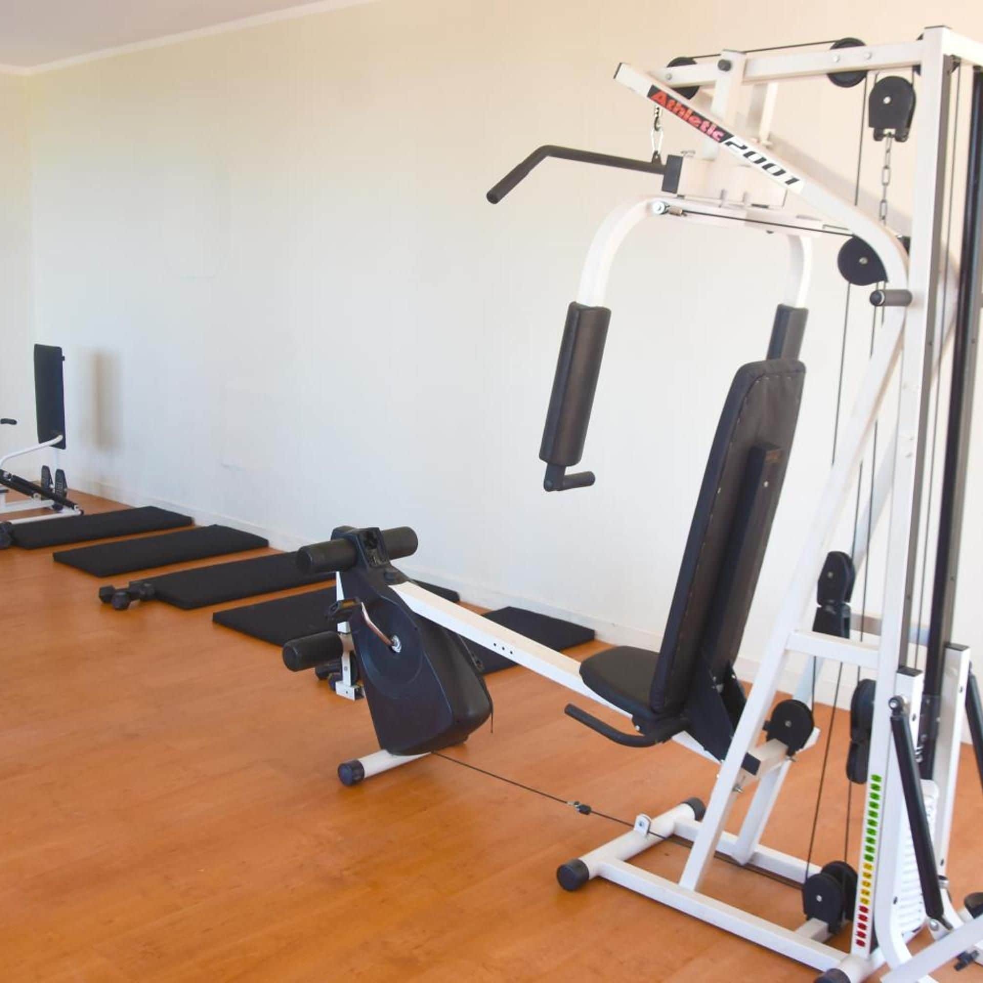 A gym with various exercise machines, including a bench press and a leg press.