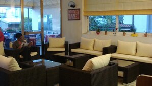 A lounge area with wicker furniture, a sofa set, and a coffee table. - Hotel Roby (Jesolo)