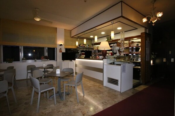 A modern restaurant with a bar area, dining tables, and chairs. - Hotel Roby (Jesolo)