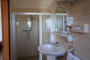 Un baño con ducha, lavamanos y toallero.