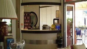 A reception area with a counter, a mirror, a lamp, and a view of the outside. - Hotel Roby (Jesolo)