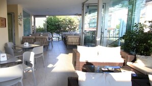 A modern outdoor seating area with wicker furniture, a glass balustrade, and a view of the cityscape. - Hotel Roby (Jesolo)